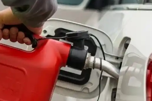 Refueling a white car with a red fuel can.