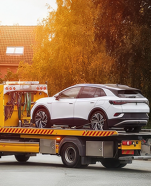 White car on a flatbed tow truck in a suburban area.