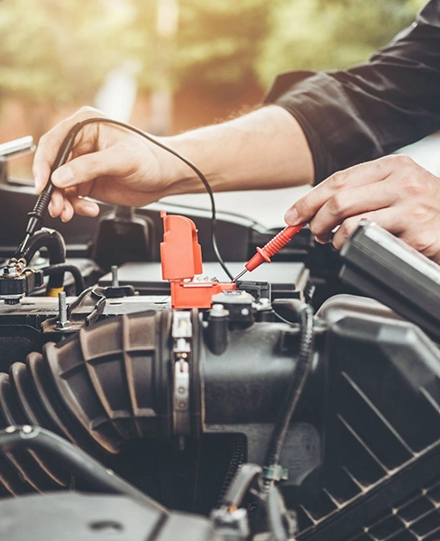 Hands attaching jumper cables to a car battery during a roadside assistance.